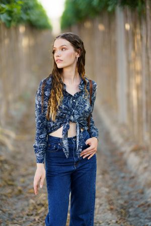 A stylish model gracefully poses in nature, surrounded by a beautiful botanical backdrop