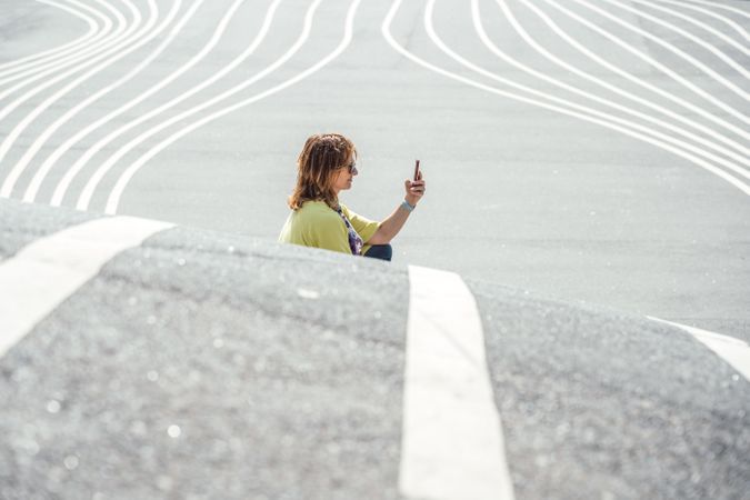 Modern relaxed woman on marked road and browsing smartphone