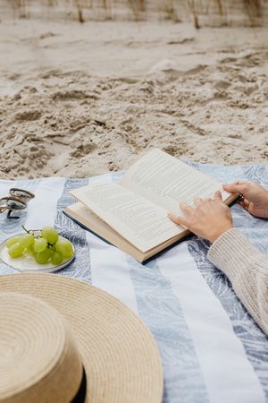 Cropped image of a person reading a book on the beach