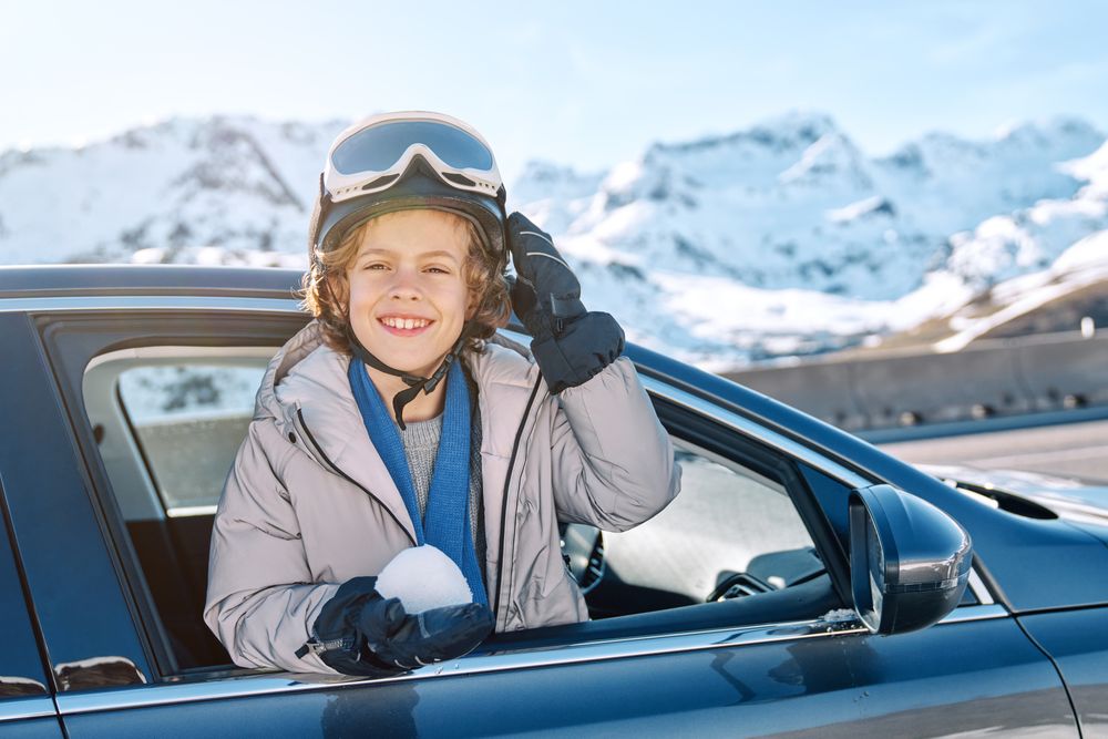 Content boy leaning out car with snowball