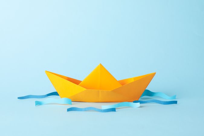 Paper boat and waves on blue background, space for text