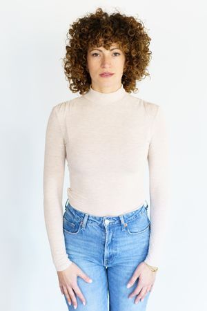 Woman with blank expression in studio shoot wearing jeans and turtleneck