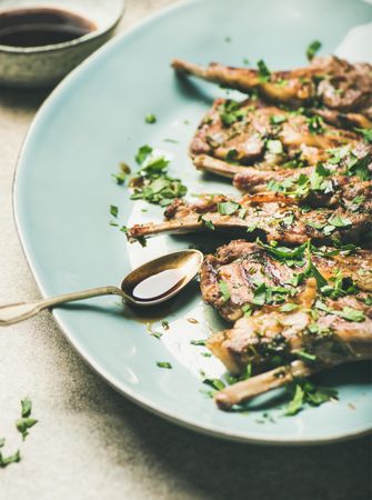 Plate of grilled lamb chops with parsley garnish on light blue plate
