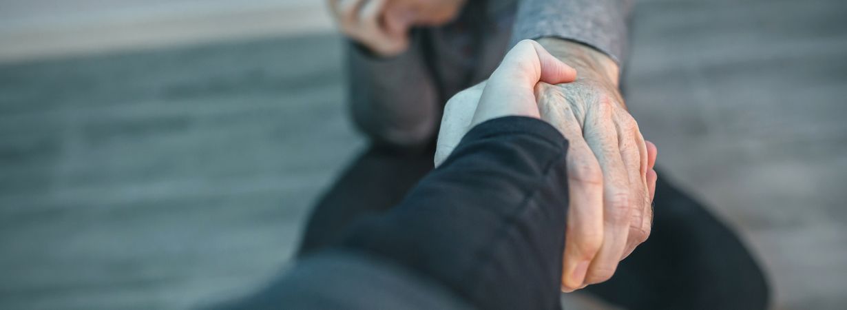 Unrecognizable man with problems receiving help from woman holding her hand