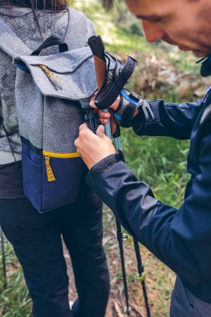 Hiker closing his partner's backpack