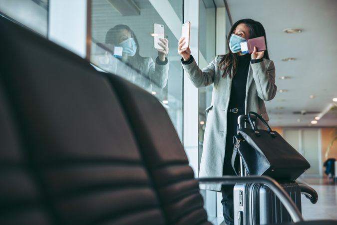 Female traveler having a video call at airport waiting lounge during pandemic