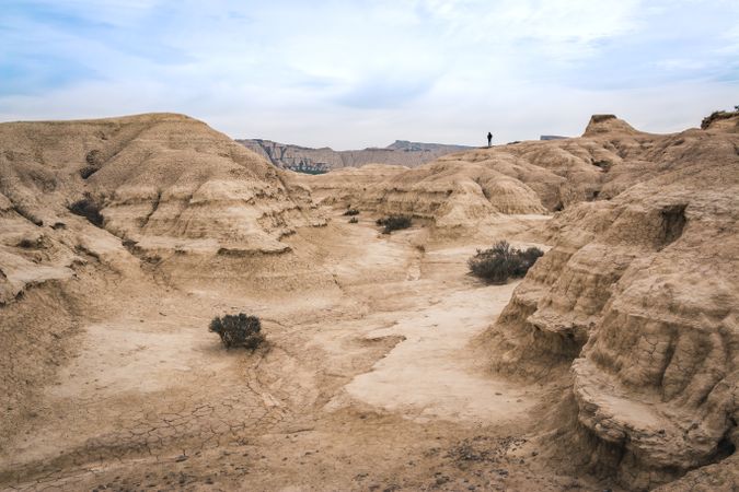 Man walking on amazing landscape of desert hills on background of blue sky