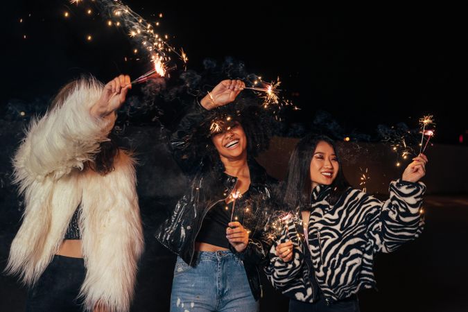 Three women walking at night with sparklers