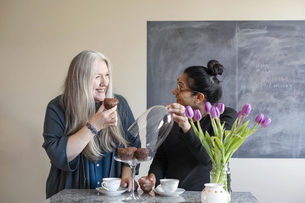 Two happy women eat chocolate muffins