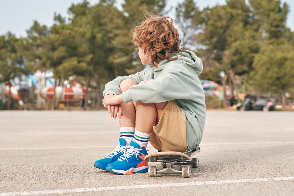 Unrecognizable teenager sitting on skateboard in city