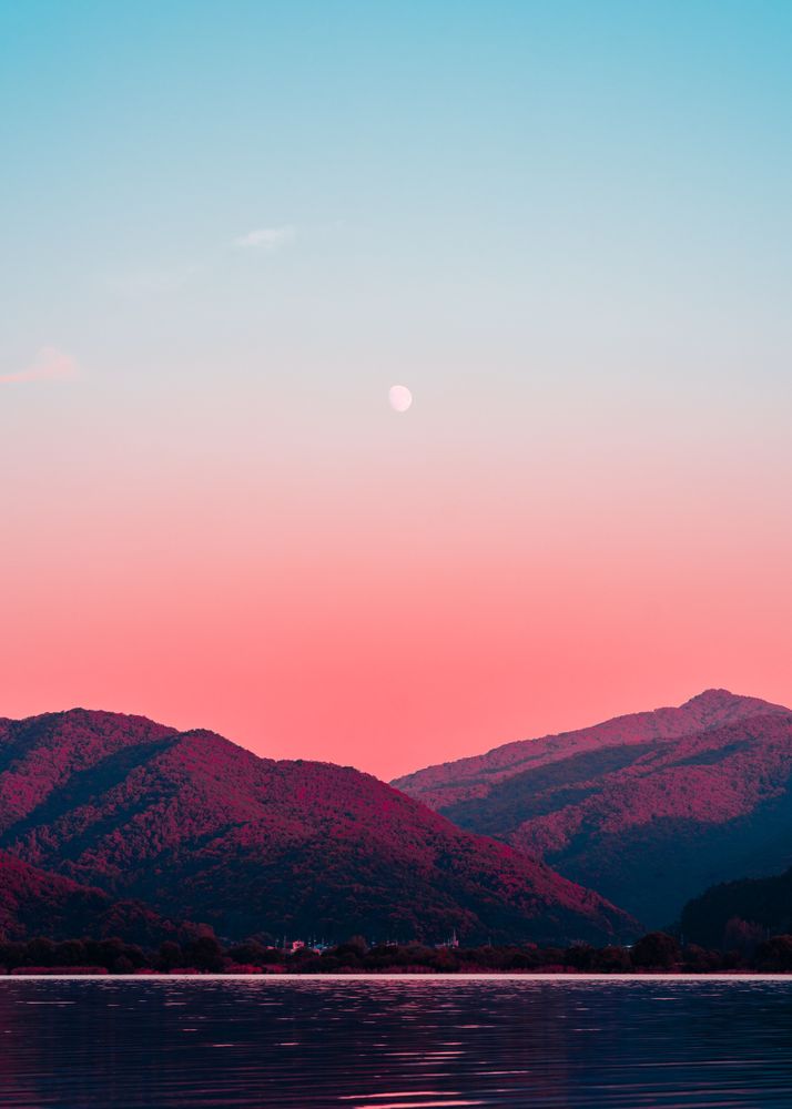 Two mountains under pink sky