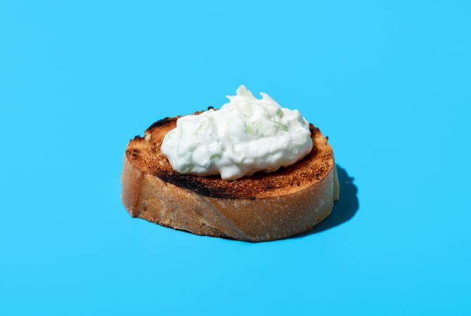 Tzatziki on toasted bread, isolated on a blue background