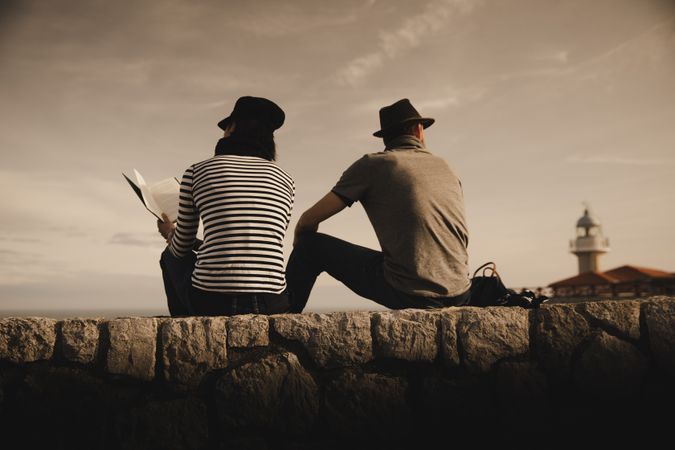 Man and woman on stones near lighthouse