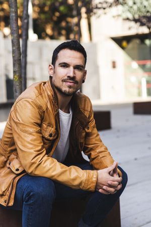 Stylish man sitting outside modern building