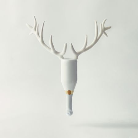 Champagne bottle with reindeer antlers on bright background