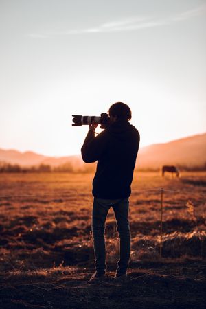 Man shooting on camera beautiful landscape between hills