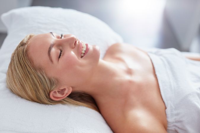Blonde woman lying back smiling with eyes closed after beauty treatment