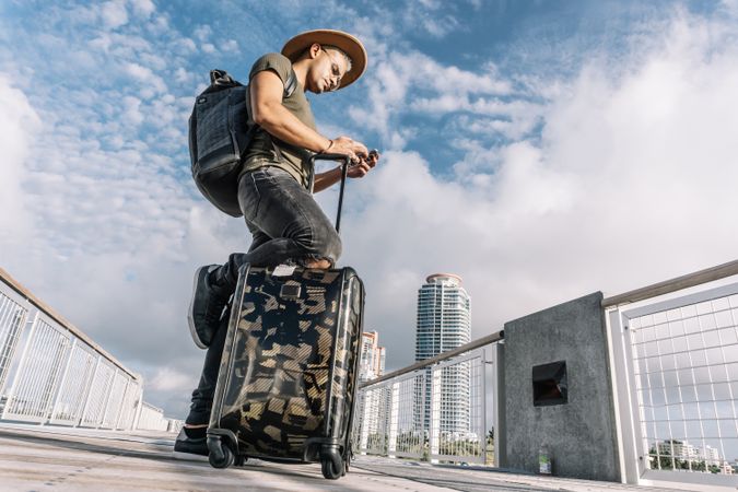 Traveller man texting phone with his luggage walking on Ocean drive South Beach Florida