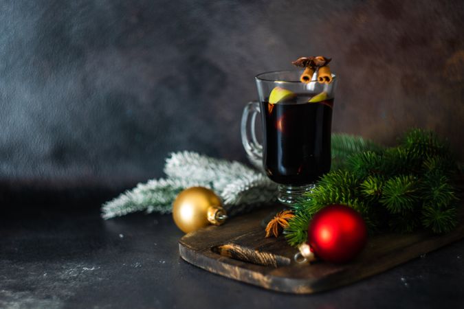 Glass of warmed mulled wine surrounded by rustic Christmas decor