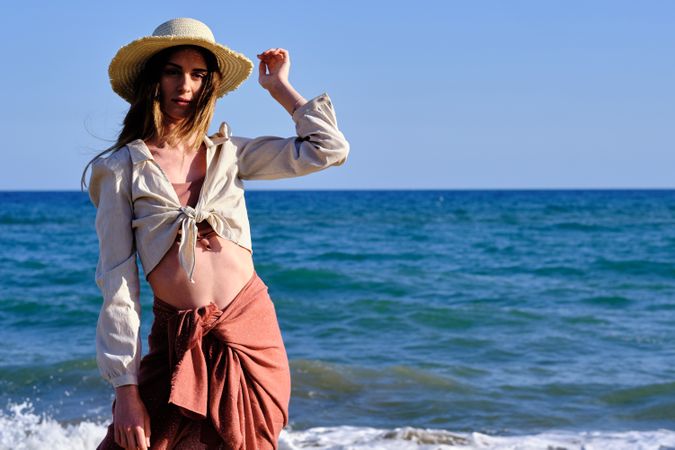A fashion model with a hat at the beach before sunset