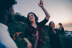 Two women and one man dance and joke around outside