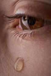 Eye of unrecognizable discontent kid with tear