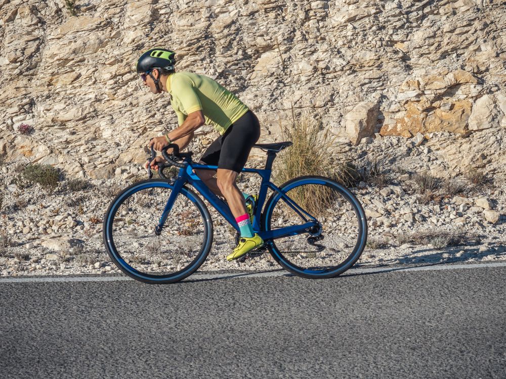 healthy man riding a bicycle on a mountain road in a sunny day