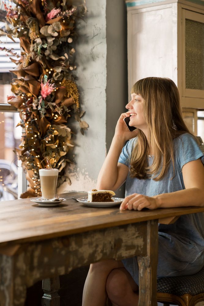 Cheerful woman talking on phone in cafe