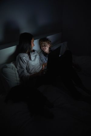 Mother and son watching film on tablet at night in bed