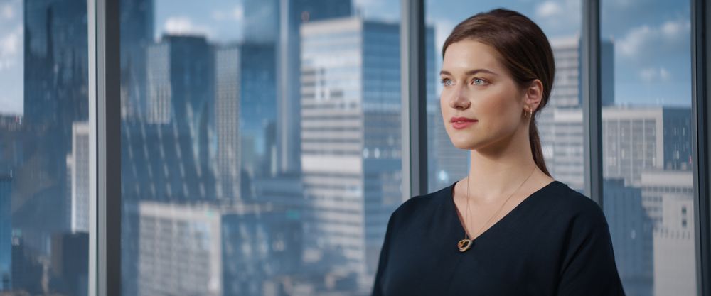 Close Up Portrait of White Businesswoman Posing Next to Window in Big City Office with Skyscrapers.