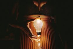 Faceless female with lightbulb in darkness