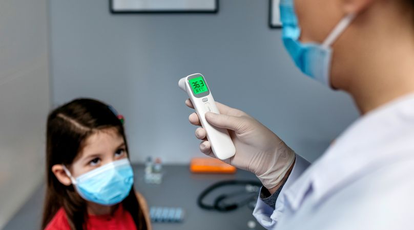 Female doctor looking at infrared thermometer after taking tempe
