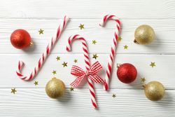 Candy canes and christmas accessories on wooden background, space for text