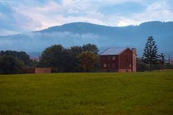 Green field and brick house near hills