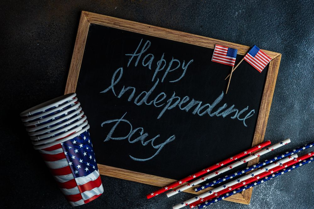 Chalkboard with the words "Happy 4th of July" with American flag straws and cups