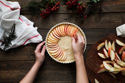 unrecognizable woman making a apple pie on a wooden table
