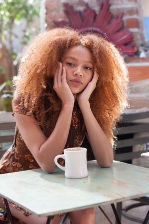 Young Black woman sitting at a table with a coffee mug