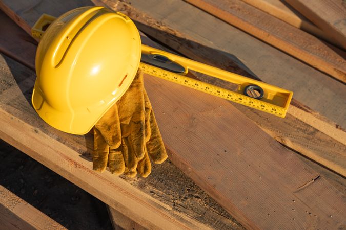 Abstract of Constrcution Hard Hat, Gloves and Level Resting on Wood Planks
