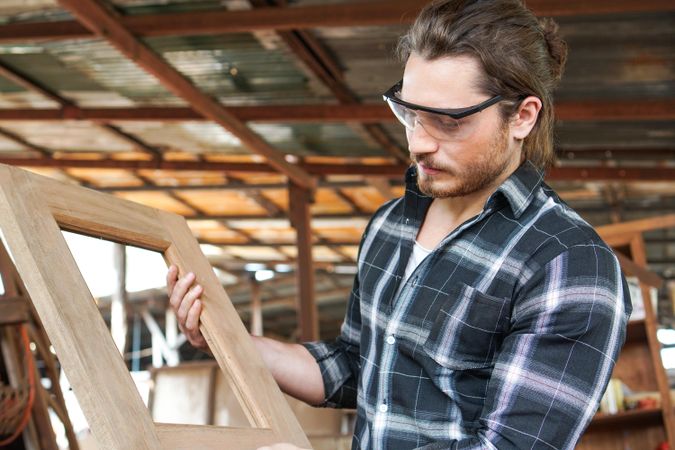 Male carpenter holding custom wooden frame