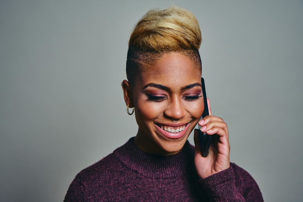 Smiling Black woman speaking on a cell phone while looking down