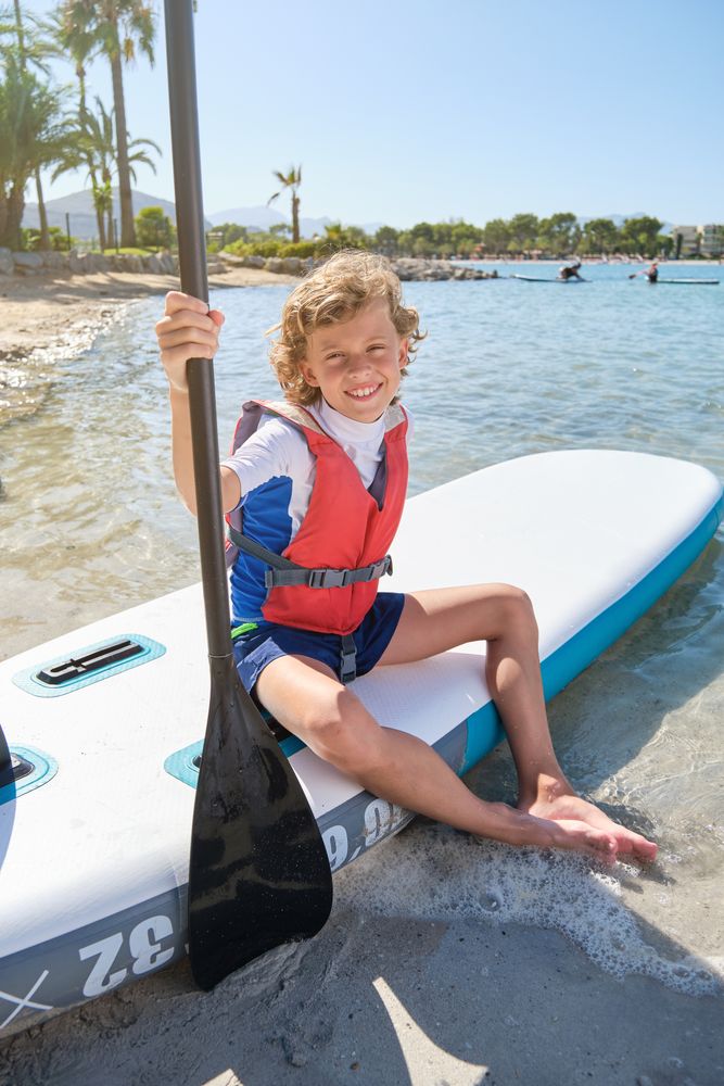 Happy kid with paddle sitting on SUP board