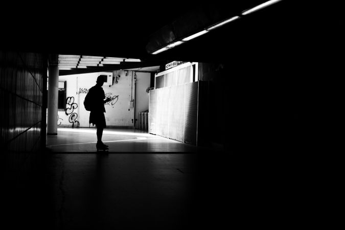 Silhouette of male skateboarding in tunnel