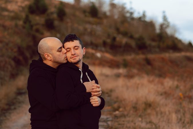 Men hugging on road on hill