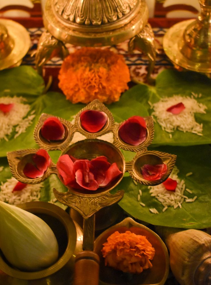Red rose petals on diya with five candle holders