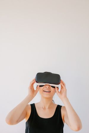 Woman using the virtual reality headset and smiling against grey background