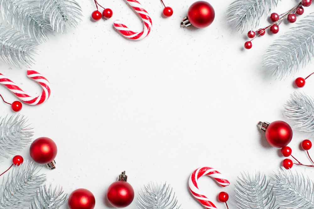 Red baubles, candy cane and frosted pine cone flat lay