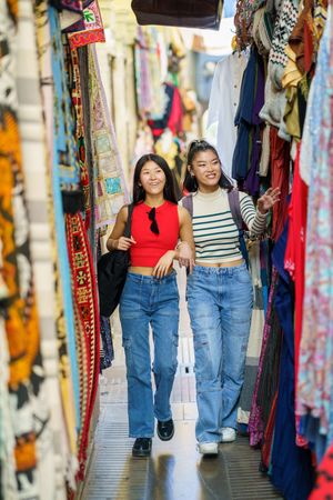 Two women walking through narrow outdoor stall