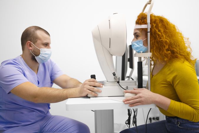 Woman having her eyes checked by male optometrist
