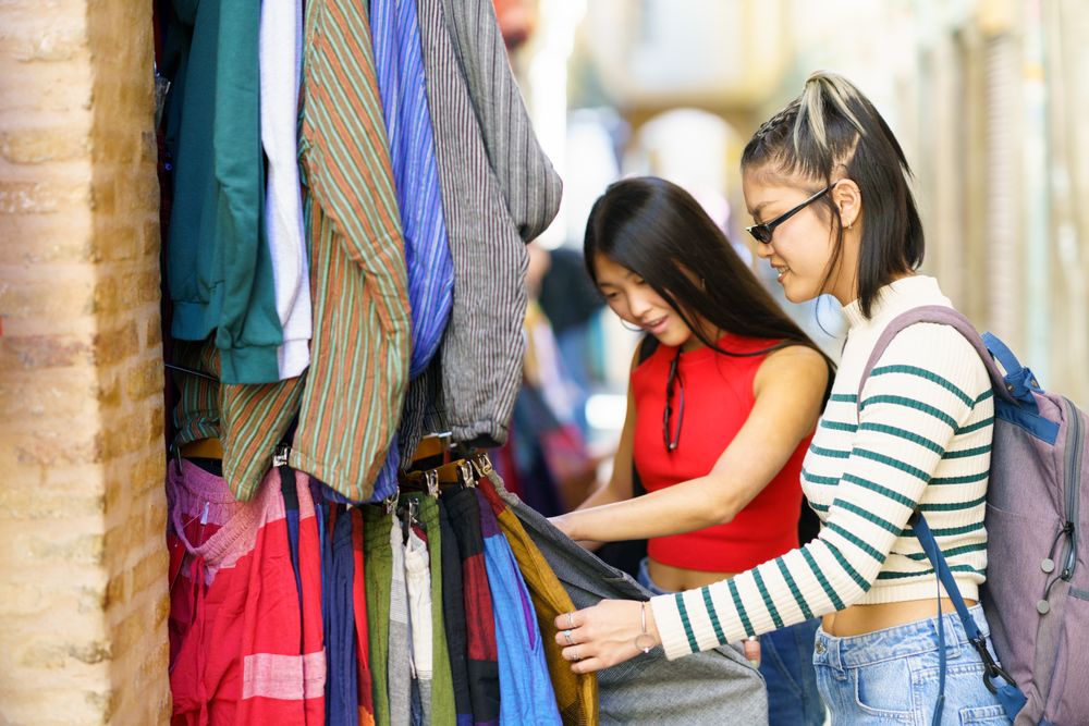 Two women looking through clothes in outdoor stall