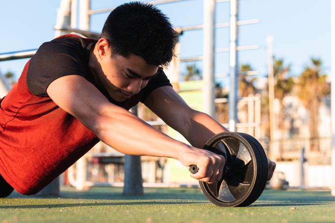 Muscular man doing ab wheel rollout exercise
